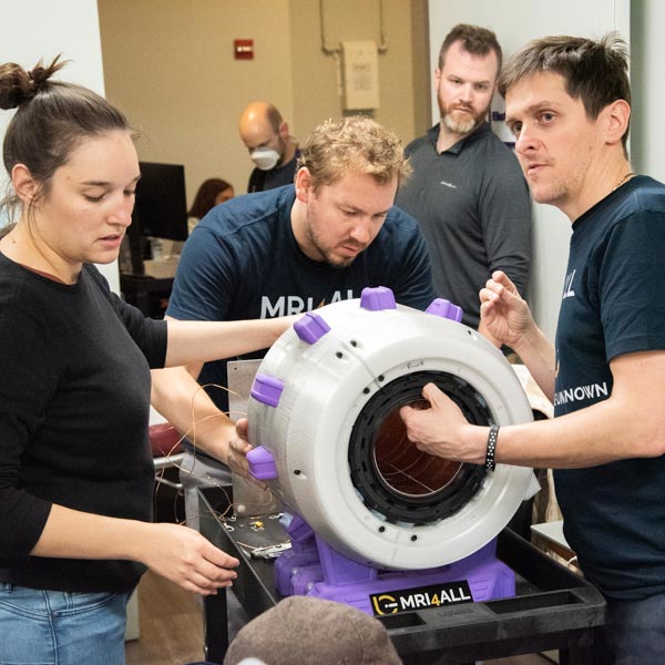 Hackathon participants seen situating the active shim/RF shield component.