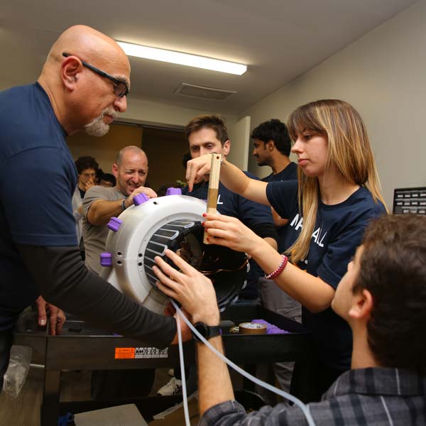 Hackathon participants seen inserting the active cooling system into the magnet.