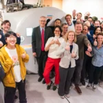 A crowd of happy researchers around an MRI scanner labeled Connectom.X.