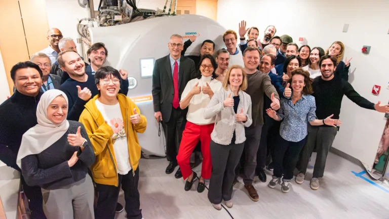 A crowd of happy researchers around an MRI scanner labeled Connectom.X.